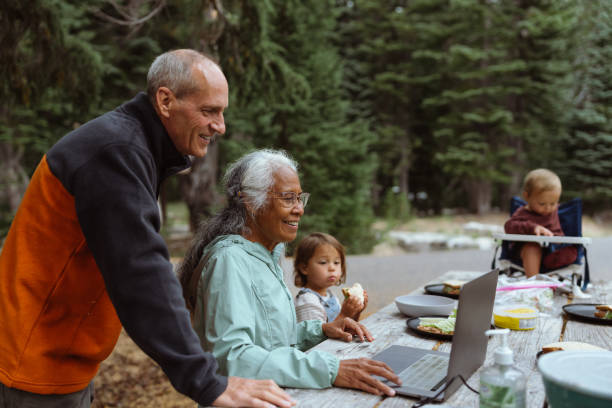 istock Active senior couple using laptop computer while camping with their grandchildren 1668771398
