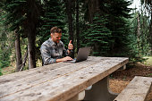 Man using laptop computer for work video call while on a camping trip