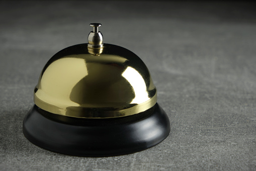 Desktop Call Bell is golden in color concrete background.Hotel reception, retro style, vintage