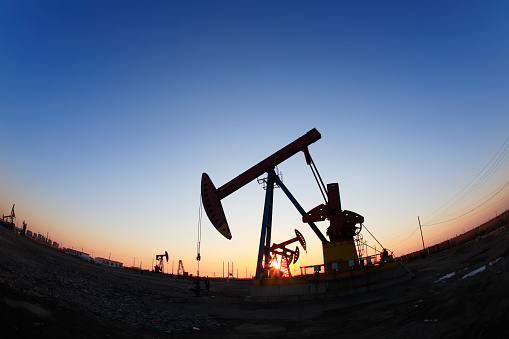 Oil field site, in the evening, oil pumps are running