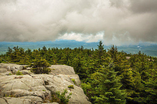 Passing dark rain cloud floating by, seen from the granite summit of Mt. Kearsarge, at Winslow State Park in Wilmot, New Hampshire