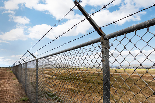 A long chain link fence with barbed wire stretches into the distance