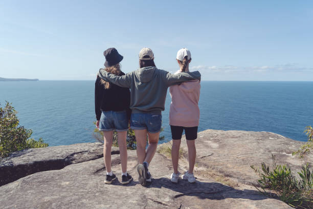 Mother and two daughters are looking at abeautiful seascape from Avalon Head, Australia