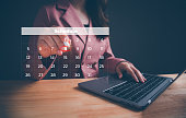 Businesswoman using pen to writing circle mark on virtual calendar agenda of booking. Highlight appointment reminders and meeting agenda on the calendar. Time management concept for effective work.