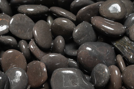 Macro photo of gray pebble stone on top of smaller stones. There are black abstract lines on big stone. Shot in studio with a full frame mirrorless camera.