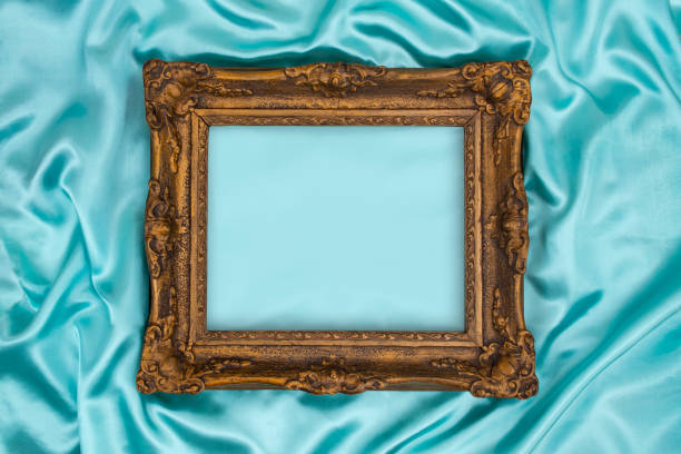 istock Beautiful classic decorated golden frame on blue, turquoise silky satin. Luxury turquoise background with blurred copy space for design. 1669111721