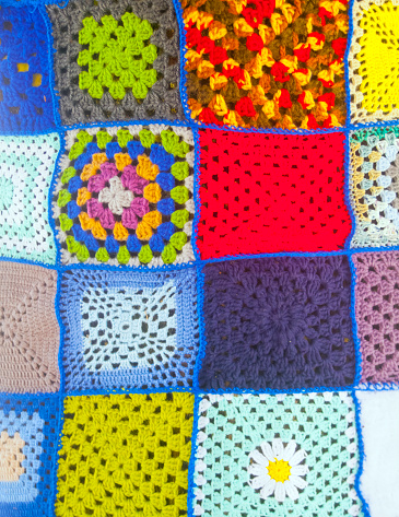 Crochet background with assorted colorful yarn and knit accessories over blue, top view, flat lay with copy space. Retro style toned