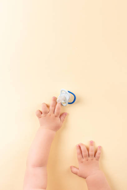 istock The baby's hands reach for the pacifier on a yellow background. Concept, top view, copy space. 1669124046