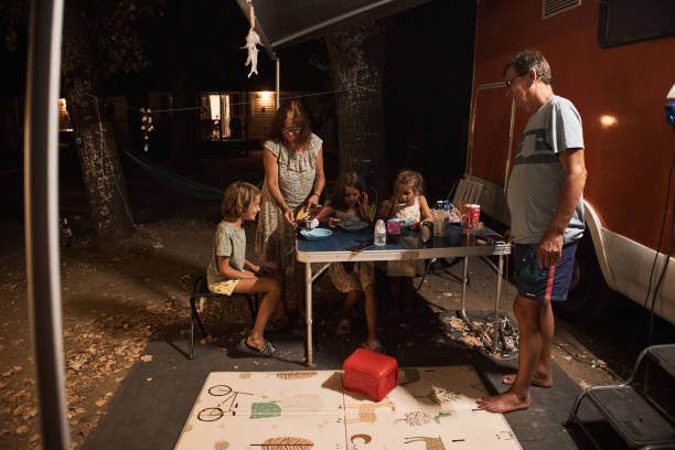 famille heureuse discutant à la table de pique-près de la caravane dans la nature - motor home mobile home camping senior adult photos et images de collection