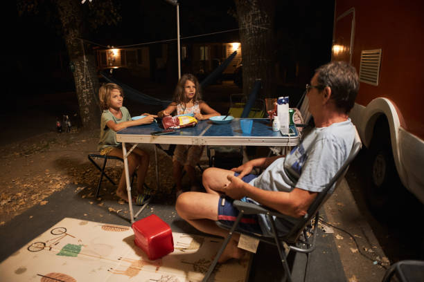 famille heureuse discutant à la table de pique-près de la caravane dans la nature - motor home mobile home camping senior adult photos et images de collection