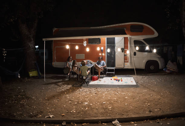 famille heureuse discutant à la table de pique-près de la caravane dans la nature - motor home mobile home camping senior adult photos et images de collection