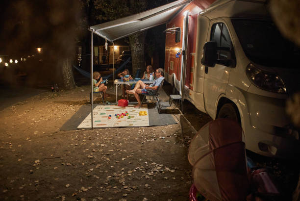 famille heureuse discutant à la table de pique-près de la caravane dans la nature - motor home mobile home camping senior adult photos et images de collection