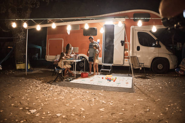 famille heureuse discutant à la table de pique-près de la caravane dans la nature - motor home mobile home camping senior adult photos et images de collection