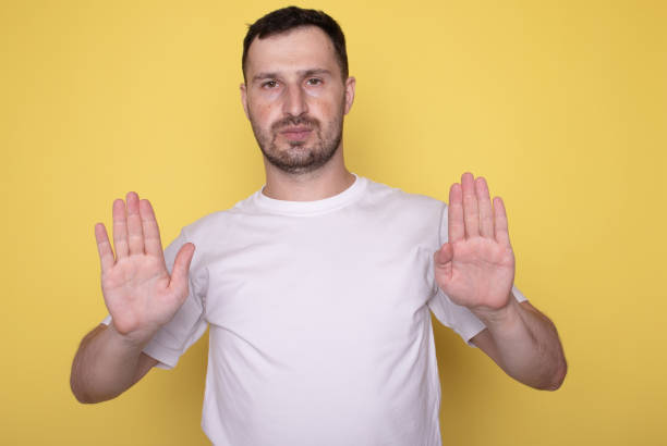 istock Man over isolated yellow background making stop gesture with hand. 1669185656