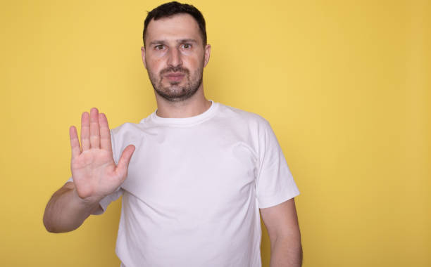 istock Man over isolated yellow background making stop gesture with hand. 1669185658