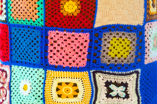 Crochet, handmade patterns and colorful threads. Colorful cotton granny square. Crochet texture close up.