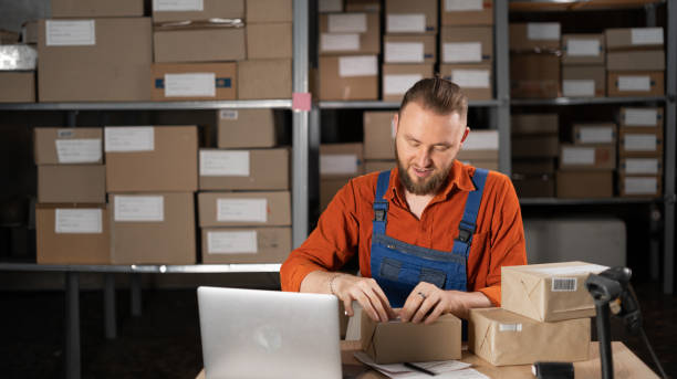 istock Warehouse worker sticking barcode label on a package box, order for shipping in a warehouse. 1669227342