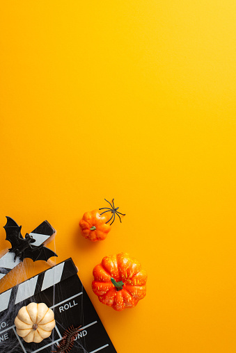 Prepare for a bone-chilling Halloween night movie marathon. Top view vertical shot of orange isolated background adorned with spooky Halloween decorations with copy-space available for advert or text