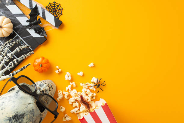 istock Embrace Halloween vibes with cinema top view featuring spooky elements like skeleton hand, skull in eyeglasses, creepy crawlies, bat, web, clapboard. Perfect for promoting ghostly movie night or event 1669270247