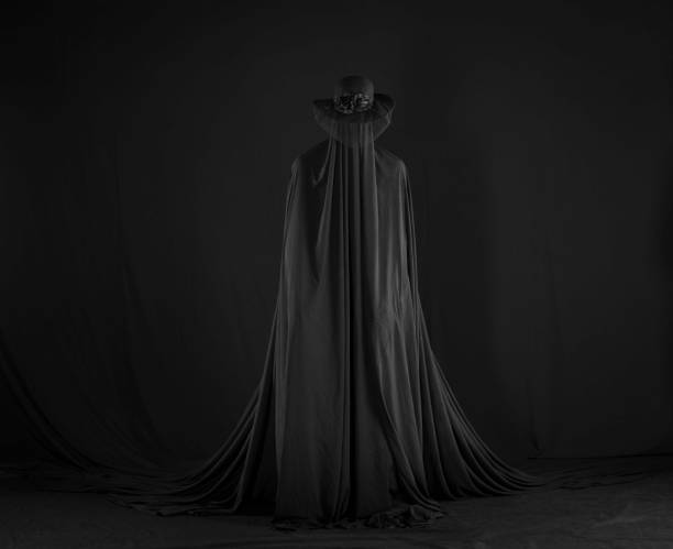 istock witch in a black cloak on a black background 1669281710