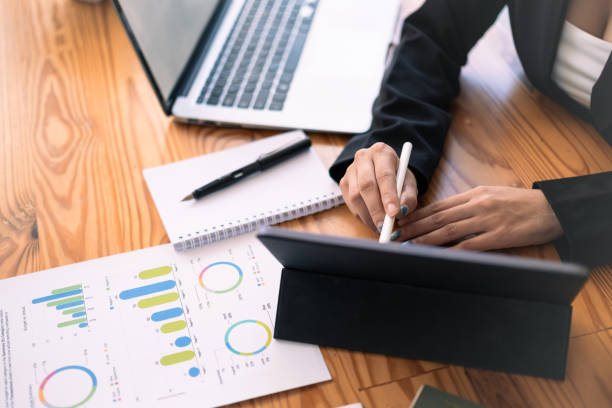 istock Businesswoman analyzing statistics document and using digital tablet on wooden office desk 1669297342