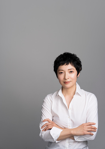 A middle-aged Japanese woman is wearing a white shirt and posing for the camera.