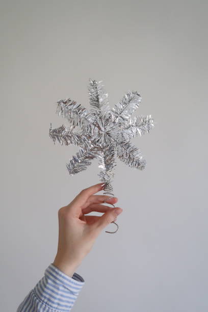 istock Woman Holding a Silver Christmas Tree Star Against White Background 1669326015