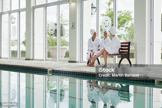 Mujer Hablando Sobre Banco Batas De Baño Junto A La Piscina Del Spa Foto de stock y más banco de imágenes de Amistad