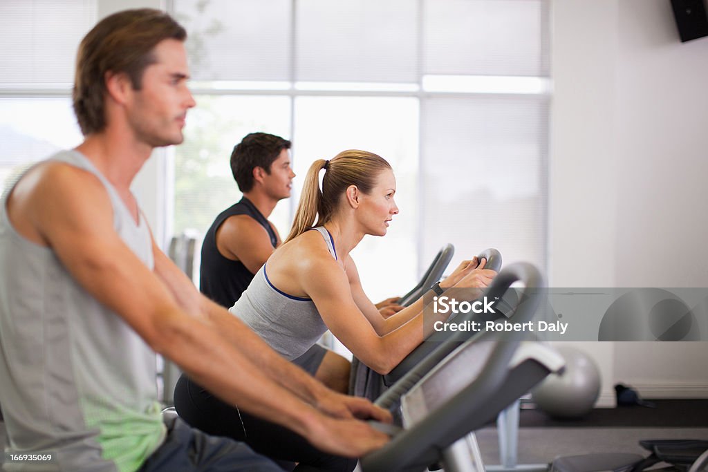 Three people on exercise bikes in gymnasium  Gym Stock Photo