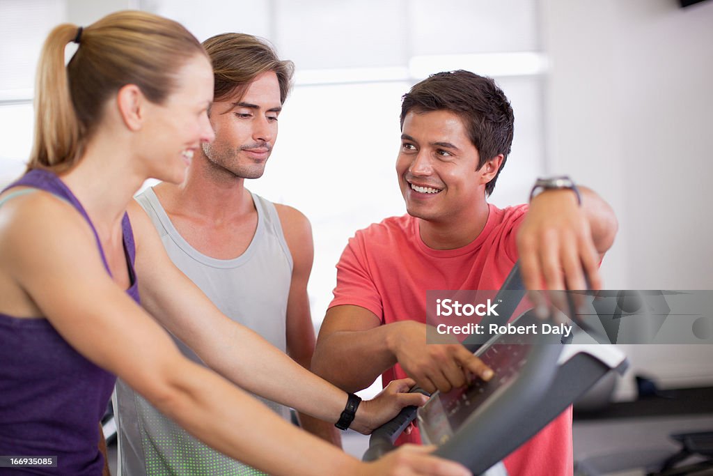 Homme aidant femme avec un tapis de course dans la salle de sport - Photo de 20-24 ans libre de droits