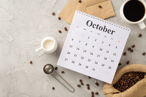 istock Coffee Bliss: Roasted coffee beans in burlap bag, espresso cup, cream jar, measuring spoon, paper bags, and calendar with October month on bright grunge background, perfect for advert 1669374340