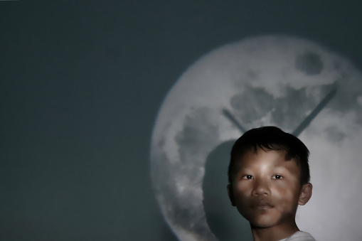 Asian boy wearing a white shirt with a clock background