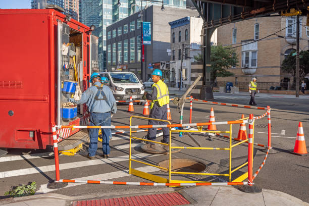 23rd Street, Long Island City, Queens, New York, USA - August 19th 2023: Hard hat workers repairing the road beneath the elevated subway tracks