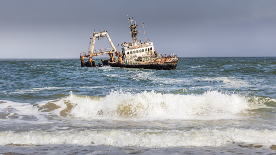 Abandoned shipwreck of the stranded Zeila vessel at the Skeleton Coast near Swakopmund in Namibia, Africa, with many cormorants sitting on the wreck.  Horizontal.