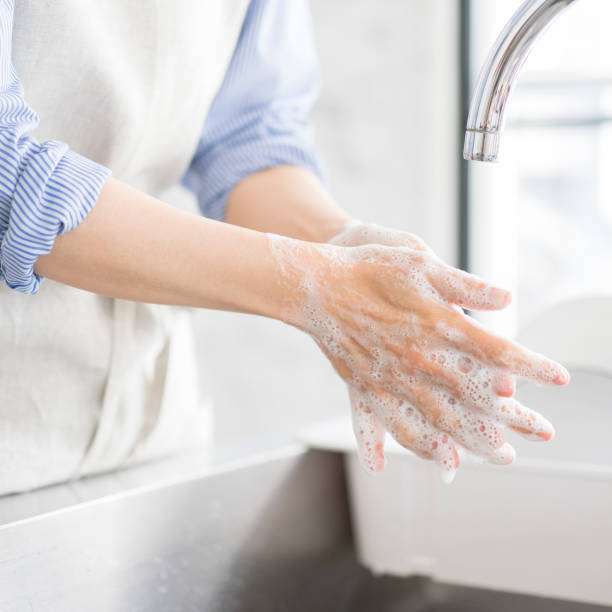 A woman is washing her hands in the kitchen.