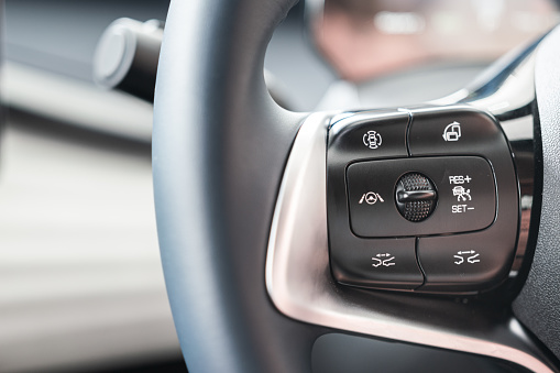 Driving assistant function buttons on multi-function steering wheel of the luxury car. Vehicle equipment part and object photo.