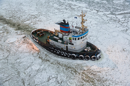 Helsinki, Finland - February 11 2014: Tug boat sailing through ice in Helsinki, Finland