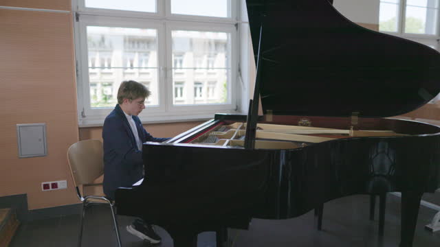 Teenage boy is practicing playing grand piano
