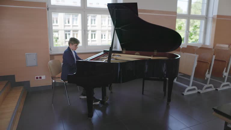 Teenage boy is practicing playing grand piano