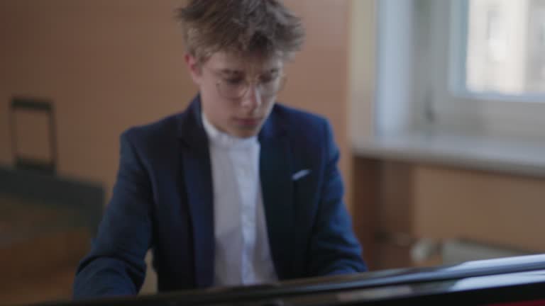 Teenage boy is practicing playing grand piano