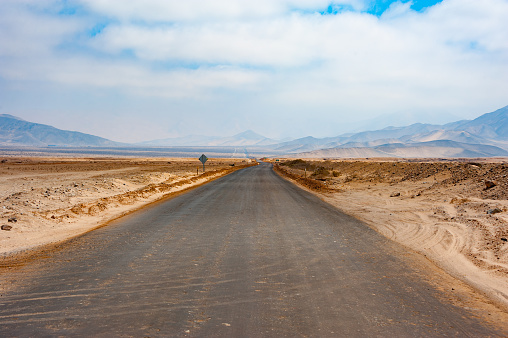 Stretching out into the seemingly endless landscape, an empty road carves its way through the Atacama Desert in Chile. Void of traffic and flanked by arid land, this desolate path offers an unbroken horizon and the quintessential experience of isolation amidst nature's extremes.