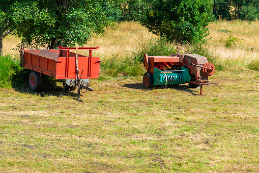 red agricultural tractor trailers on green meadow