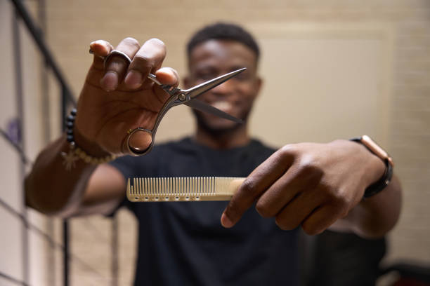 Hairdresser holds a working tool in his hands Hairdresser holds a working tool in his hands, the master has curly hair black barber stock pictures, royalty-free photos & images
