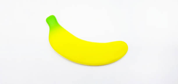 白い背景に偽のバナナ。小さなおもちゃ、形、オブジェクトのコンセプト。 果物の本物ではありません - sex toy ストックフォトと画像