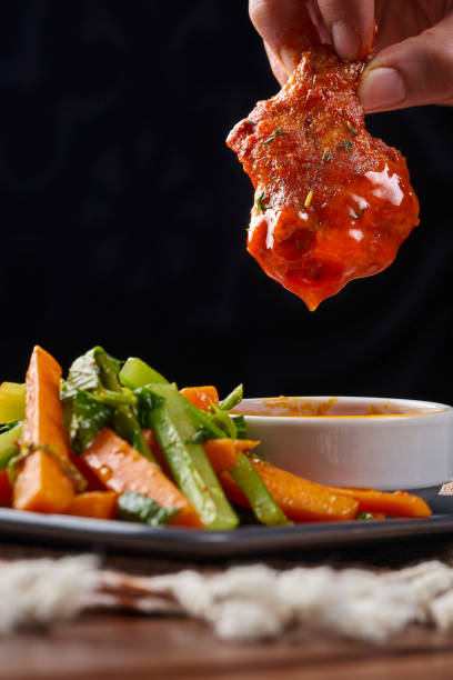 istock Fried chicken wings with spicy buffalo sauce and boiled vegetables 1669704521