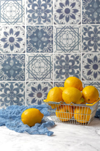 istock Wire Basket of Fresh Lemons on White Kitchen Counter with Blue Tile Background 1669751518