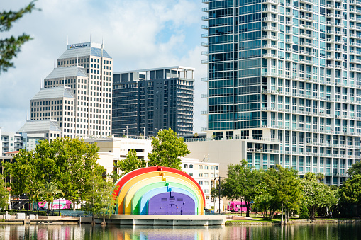 In Orlando, USA the downtown cityscape including the rainbow painted amphitheater reflects in Lake Eola on a summer day in Florida.