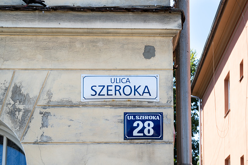 Szeroka street name sign in the historic Jewish Quarter Kazimierz district of old town Krakow, Poland. Information plate on building wall in Kraków. Broad Street square in Cracow.