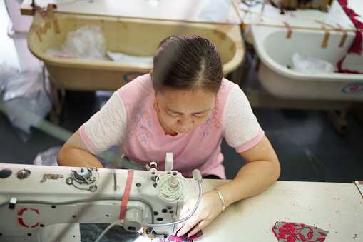Asian female worker using sewing machine