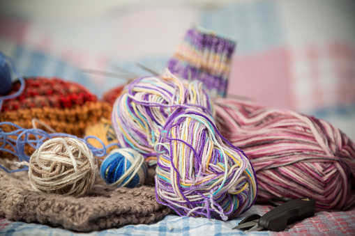 Colored threads, knitting needles and other items for hand knitting, on the bed .